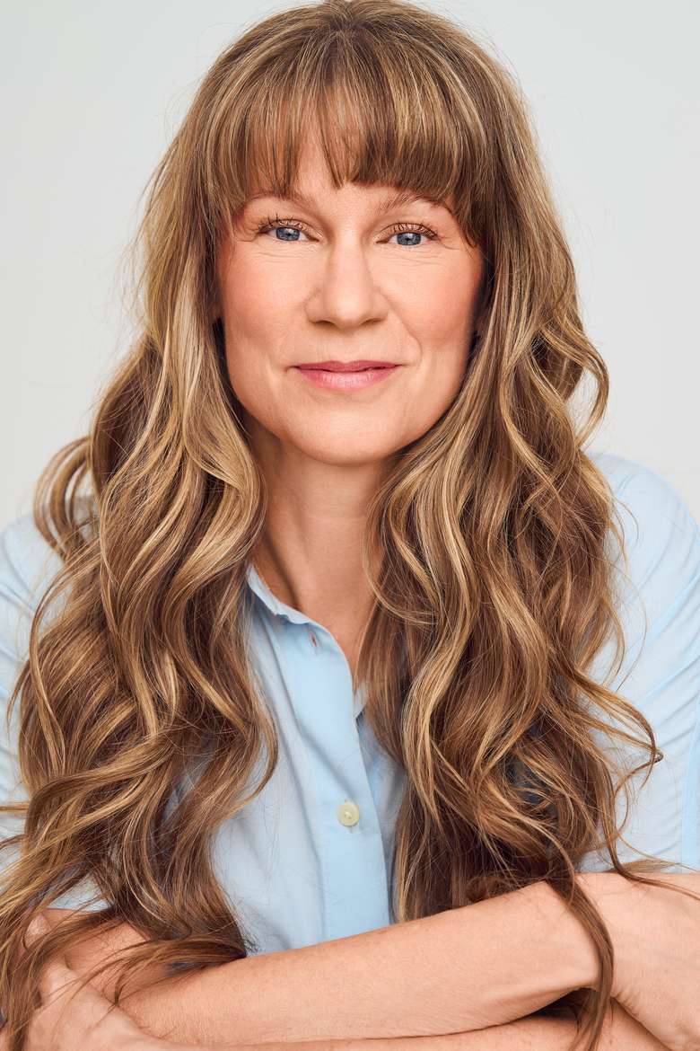 Femme souriante aux cheveux longs et blonds.